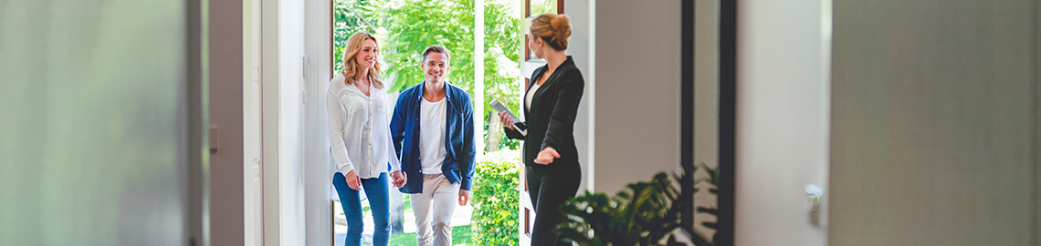 Immobilienmakler zeigt einem jungen Paar ein neues Haus