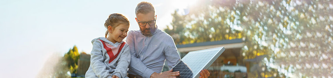 Vater zeigt seiner kleinen Tochter Solar-Photovoltaik-Module, erklärt, wie es funktioniert. Alternative Energie, Ressourcenschonung und nachhaltiges Lifestyle-Konzept.