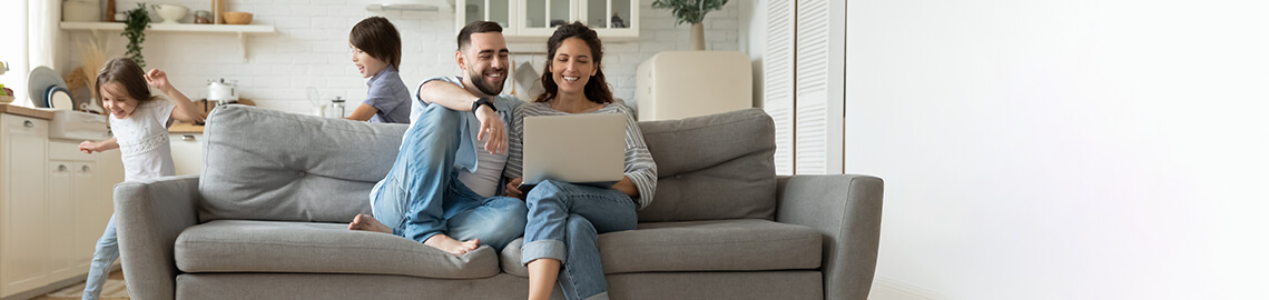 Während aktive Kinder laufen Eltern ruhen auf dem Sofa mit Laptop